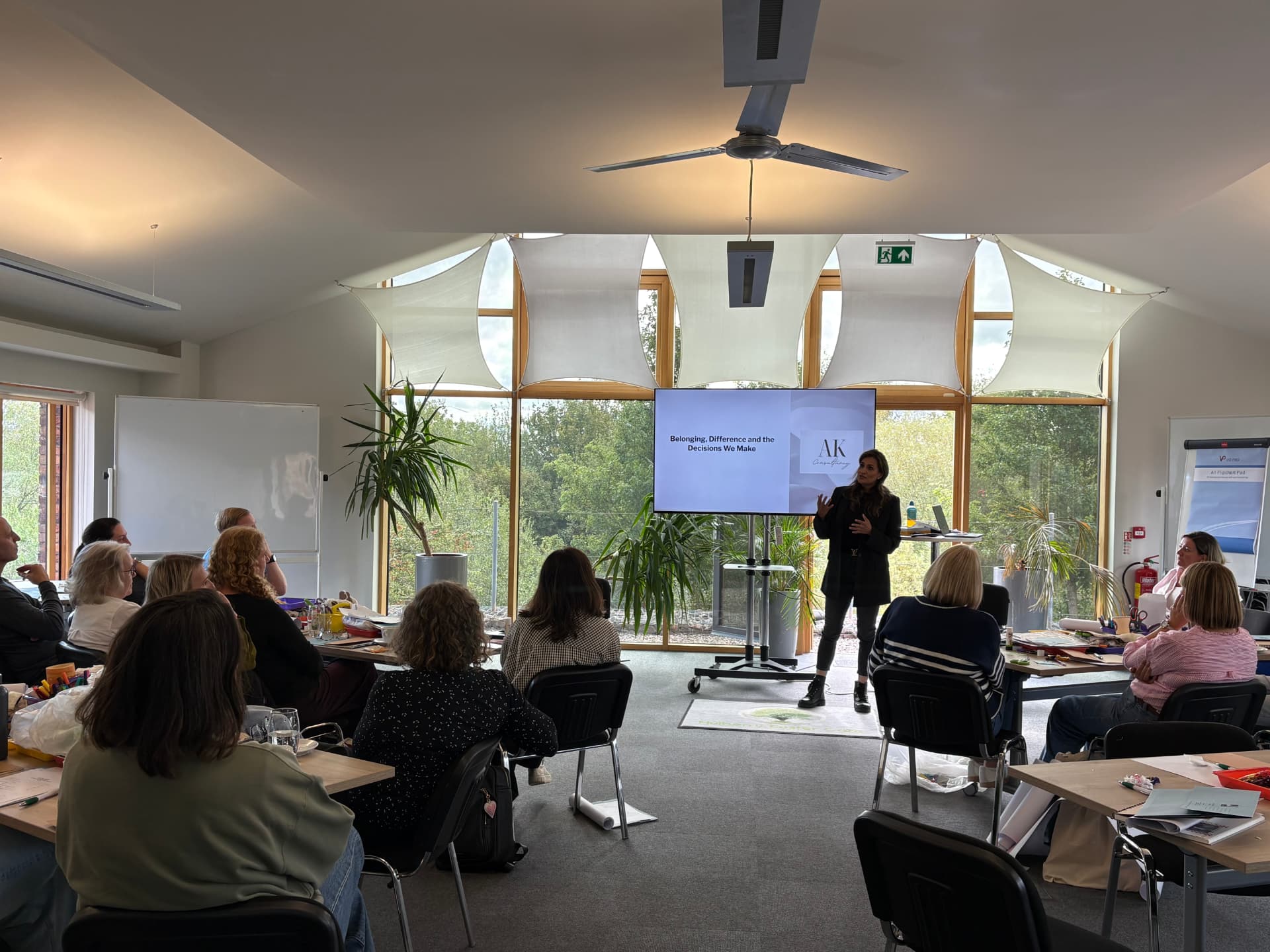 Anira Khokhar presenting to a large workshop audience seated at tables