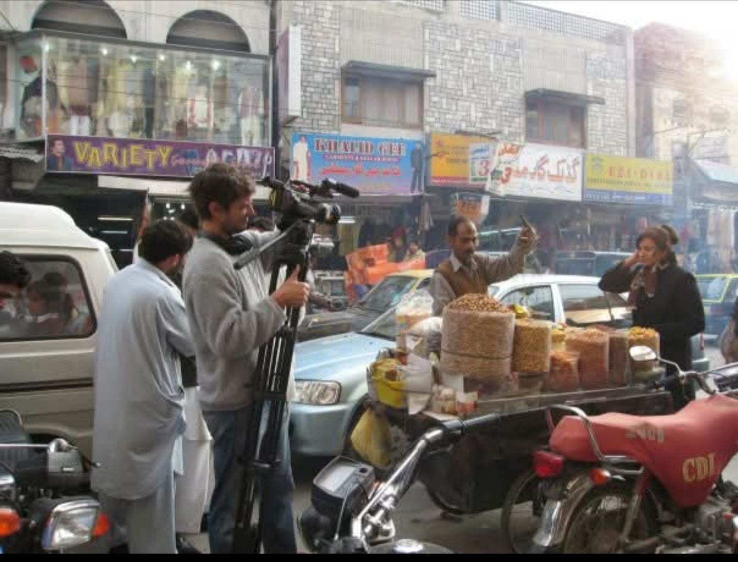A camera crew filming Anira Khokhar beside a market stall in Pakistan for a documentary