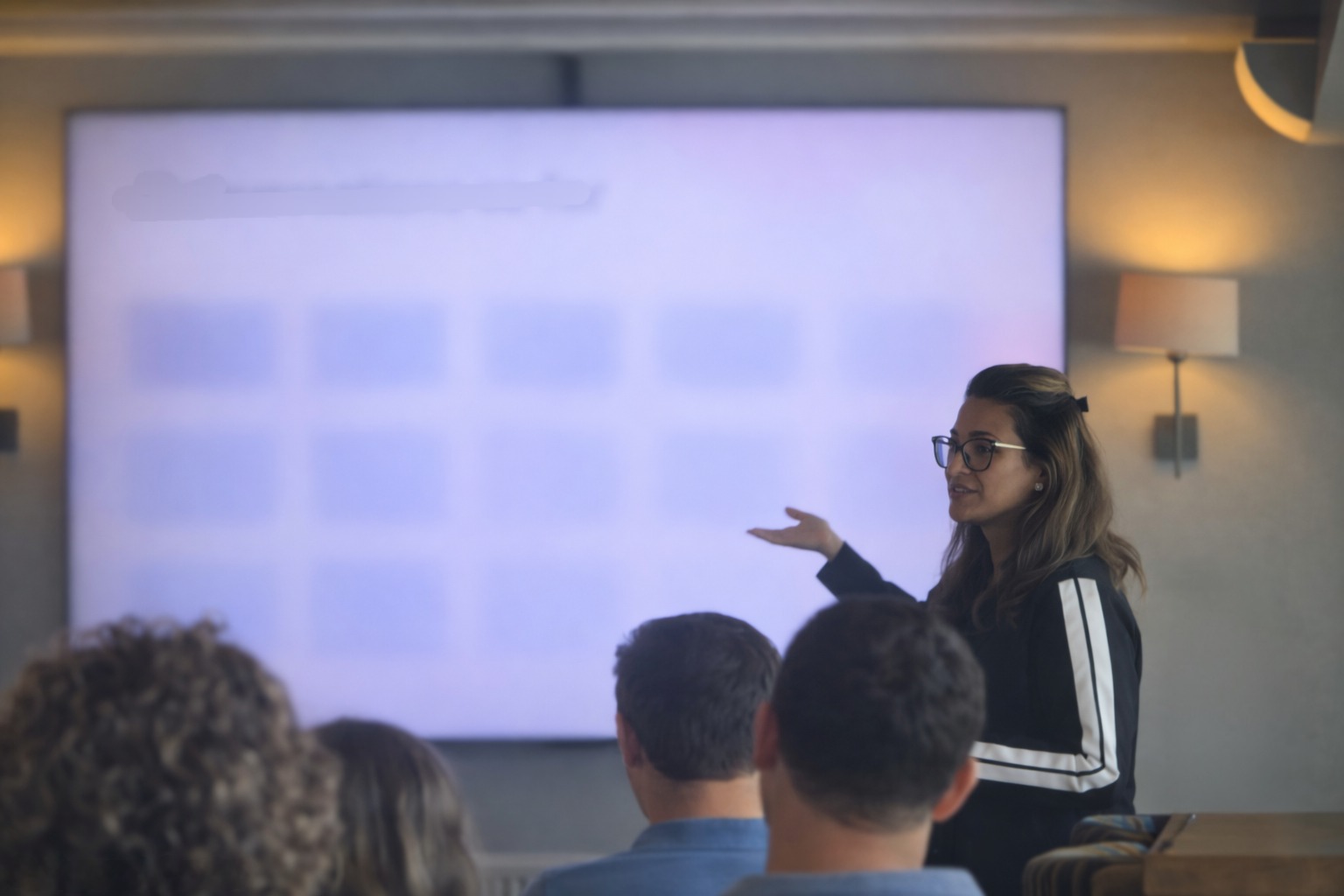 Anira Khokhar presenting beside a large display screen to a seated workshop audience